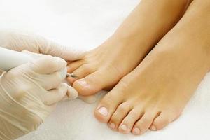 Pedicure master work. Close up of female nails and pedicurist hands in gloves with special tool. photo