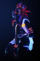Model in image of Native american with neon makeup, which made of fluorescent paint in ultraviolet light. photo