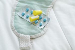 Earplugs, blindfold and sleeping pills on bed photo