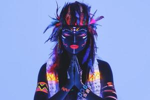 modelo a imagen de nativo americano con maquillaje de neón, hecho de pintura fluorescente en luz ultravioleta. foto
