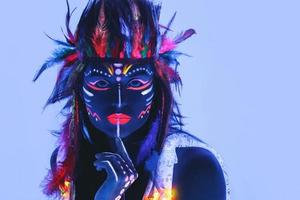 Model in image of Native american with neon makeup, which made of fluorescent paint in ultraviolet light. photo