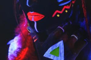 Model in image of Native american with neon makeup, which made of fluorescent paint in ultraviolet light. photo