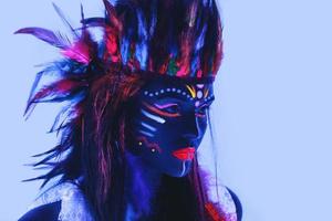 Model in image of Native american with neon makeup, which made of fluorescent paint in ultraviolet light. photo