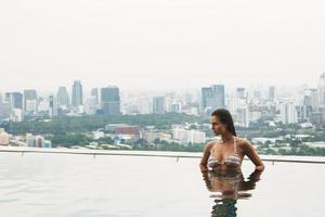 mujer relajándose en una piscina en la azotea con una hermosa vista de la ciudad foto