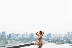 Woman relaxing on a rooftop pool with a beautiful city view photo