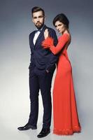 mujer con hermoso vestido rojo y hombre con traje clásico azul con pajarita. foto