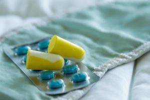 Earplugs, blindfold and sleeping pills on bed photo