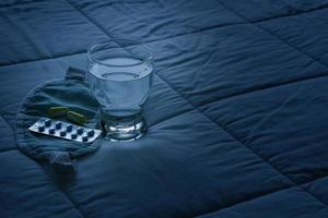 Blister pack of sleeping pills, blindfold and glass of water photo