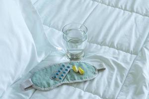 Blister pack of sleeping pills, blindfold and glass of water photo