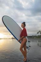 Young and sexy woman with a longboard during surfing session on the beach photo