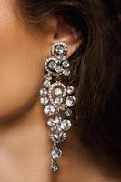 Ear and beautiful big earring with a lot of gemstones photo