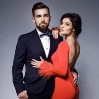 mujer con hermoso vestido rojo y hombre con traje clásico azul con pajarita. foto