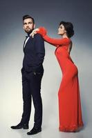 mujer con hermoso vestido rojo y hombre con traje clásico azul con pajarita. foto