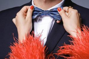 Woman is helping to fit up a bow tie to her man photo