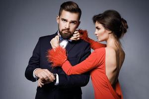 mujer con hermoso vestido rojo y hombre con traje clásico azul con pajarita. foto