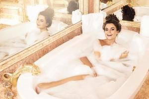 mujer feliz y hermosa se está bañando con espuma foto
