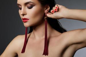 Stunning woman with a beautiful makeup wearing long red earrings photo