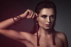 Stunning woman with a beautiful makeup wearing long red earrings photo