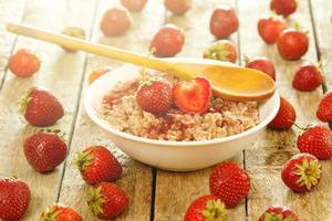 Cooked oatmeal, ripe berries and strawberry jam photo