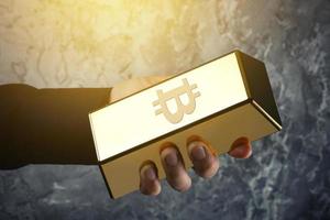 mano masculina y lingotes de oro con el símbolo de bitcoin foto