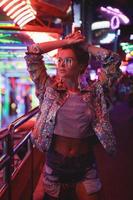 Woman wearing sparkling jacket on the city street with neon lights photo