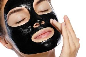 Beautiful woman with a purifying black mask on her face photo