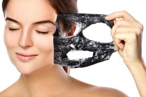 Beautiful woman is removing purifying mask from her face photo