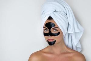 Young and beautiful woman with black peel-off mask on her face photo