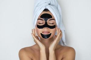 Young and beautiful woman with black peel-off mask on her face photo