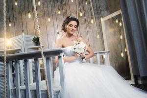 joven novia feliz con un hermoso vestido exuberante en la habitación con muchas bombillas foto