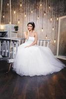 Young happy bride wearing beautiful lush dress in the room with a lot of light bulbs photo