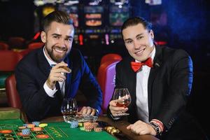 Handsome guys drinking cognac and playing roulette in the casino photo