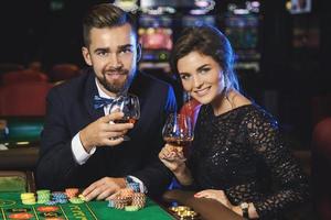 hermosa y rica pareja jugando a la ruleta en el casino foto