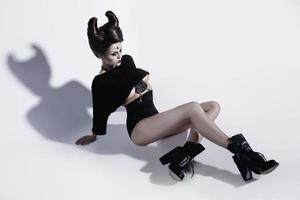 Model in creative image. Spooky porcelain doll with horns on her head. photo