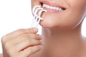 Mujer con selección de hilo dental sobre fondo blanco. foto