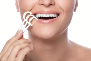 Woman with dental floss pick on white background photo