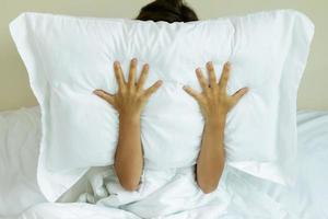 Woman with pillow on her head because she don't wanna hear noise photo