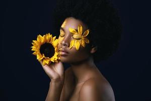 African woman with a sunflower and creative makeup on her face photo