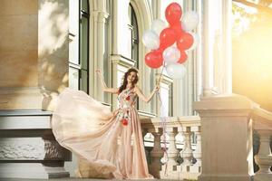 Woman in beautiful dress with a lot of colorful balloons photo