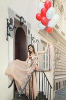 Woman in beautiful dress with a lot of colorful balloons photo