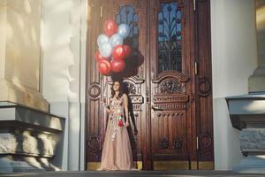 Woman in beautiful dress with a lot of colorful balloons photo