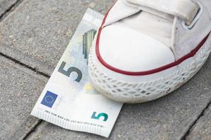 Female foot and five euro banknote on the ground photo