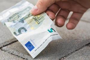 Woman is picking five euro banknote from the ground photo