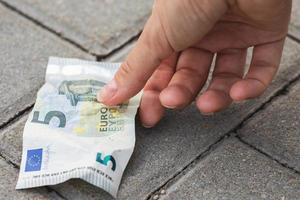 Woman is picking five euro banknote from the ground photo
