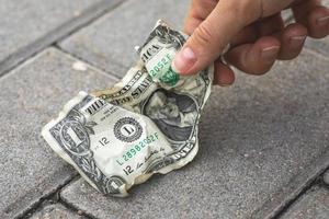 Poor woman picking old and crumpled one dollar bill photo