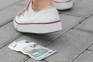 Female foot and five euro banknote on the ground photo