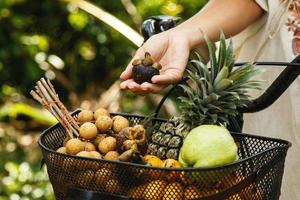Basket on the bicycle full of different exotic fruits photo
