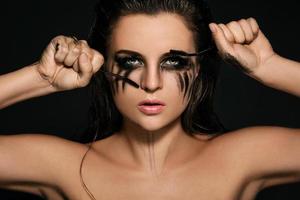 Woman with smudges of makeup on her face and broken mascara brushes photo