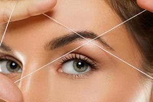 Eyebrow threading - epilation procedure for brow shape correction photo