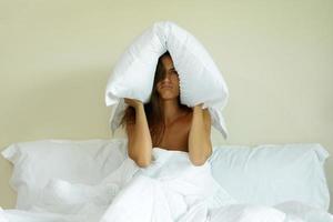 Woman with pillow on her head because of noise photo